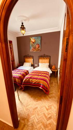 a bedroom with two beds and a large mirror at apparemment 3 ème étage à-côtés de la plage in Essaouira
