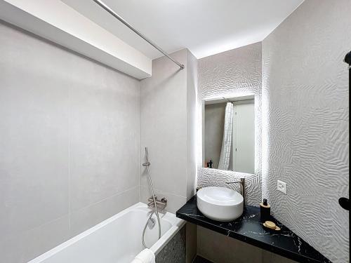 a white bathroom with a sink and a bath tub at La Duchesse in Crans-Montana