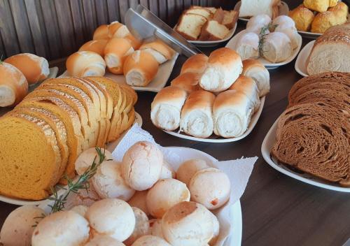 a table with various types of bread and pastries on plates at iG Pousada - Frente Mar in Florianópolis