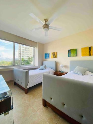 a bedroom with two beds and a large window at Great Beachfront Amara Condo Ixtapa in Ixtapa