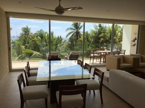 イスタパにあるGreat Beachfront Amara Condo Ixtapaのテーブルと椅子と大きな窓のあるダイニングルーム