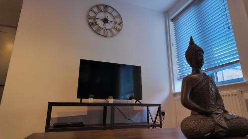 a living room with a clock on the wall and a statue at City Center 1 Bed Flat in Peterborough
