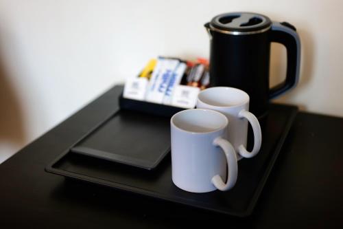 two white coffee mugs sitting on a black tray at Clifton House Brighton in Portslade