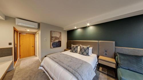 a bedroom with a large bed and a green wall at Distinction Luxmore Hotel in Te Anau
