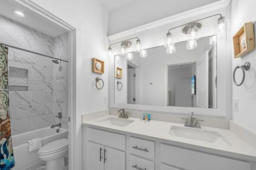 a white bathroom with two sinks and a mirror at Sandy Cheeks in Orange Beach