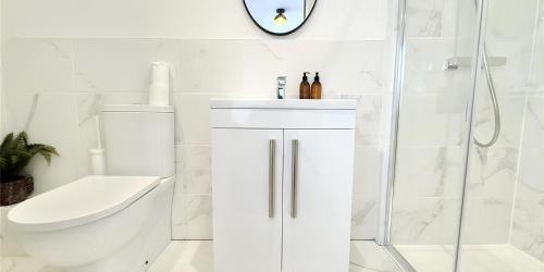 a white bathroom with a toilet and a sink at Chapel House Luxury Apartments Hoylake in Birkenhead