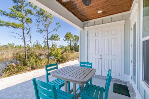 a table and chairs on a porch with a door at Sandy Cheeks in Orange Beach