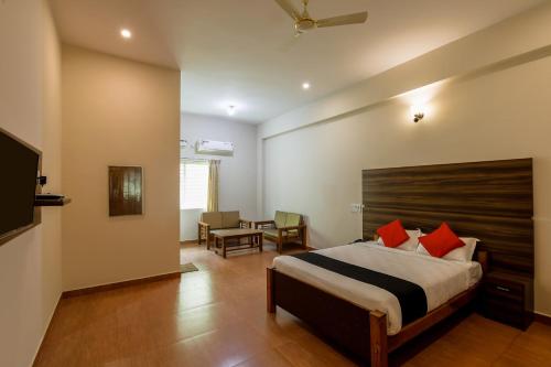 迈索尔Townhouse J K Golden Embassy的一间卧室配有一张带红色枕头的床和一张桌子