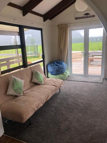 a living room with a couch and a sliding glass door at Atiamuri Family Bach in Atiamuri