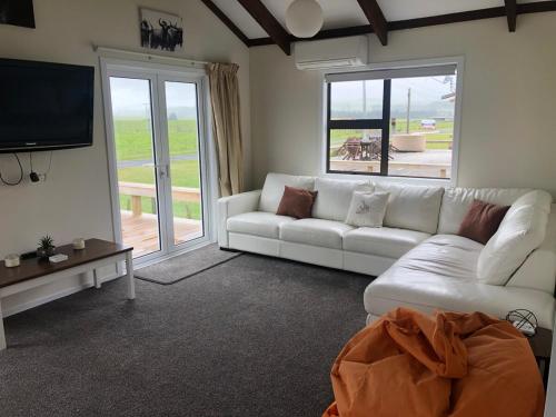 a living room with a white couch and a television at Atiamuri Family Bach in Atiamuri