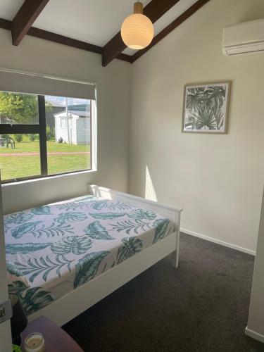 a bedroom with a bed and a large window at Atiamuri Family Bach in Atiamuri