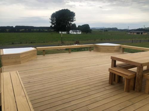 a wooden deck with two benches on top of it at Atiamuri Family Bach in Atiamuri