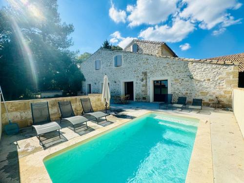 a villa with a swimming pool in front of a building at Les Rives du Parc Piscine 12 personnes in Lédenon