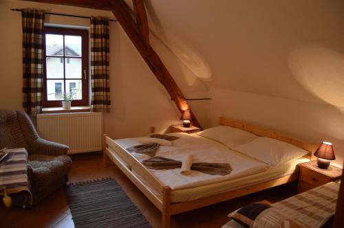 a bedroom with a bed and a chair and a window at Restaurace a penzion U Lva in Karlštejn