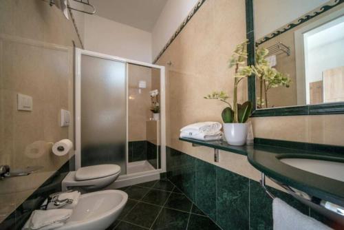 a bathroom with two toilets and a sink and a mirror at Hotel Bellevue in Cattolica
