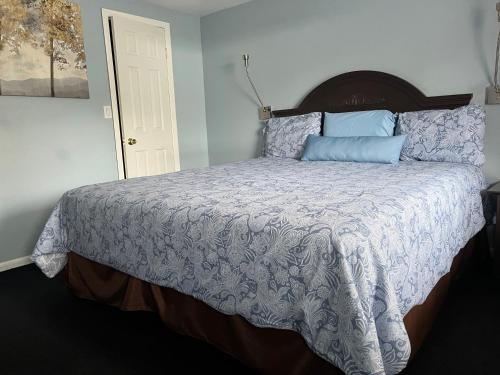 a bedroom with a large bed with blue pillows at Hitching Post Motel in Cornwall