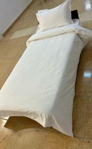a bed with white sheets and pillows on the floor at فندق حياة حقل الفندقية Hayat Haql Hotel in Al Humaizah