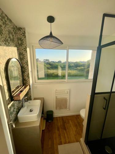 une salle de bain avec un lavabo, un miroir et une fenêtre dans l'établissement Maison lumineuse, 3 chambres, avec jardin, à Quiberon