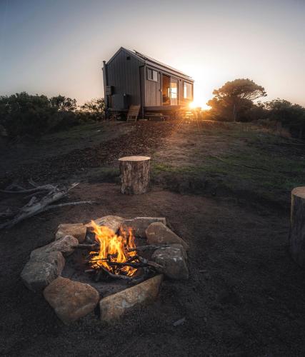 a fire pit in front of a cabin at Beach Front Off-Grid Cabin on Kangaroo Island - Rae in Antechamber Bay