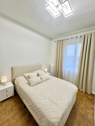 une chambre blanche avec un grand lit et une fenêtre dans l'établissement Bel appartement centre ville, à Limoges