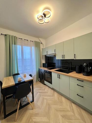 une cuisine avec des armoires blanches et une table et une salle à manger dans l'établissement Bel appartement centre ville, à Limoges