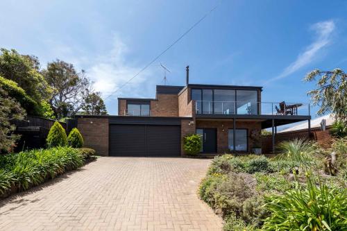 a brick house with a balcony on top of it at The Lookout Retreat in Anglesea