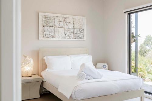 a white bedroom with a bed with towels on it at The Lookout Retreat in Anglesea