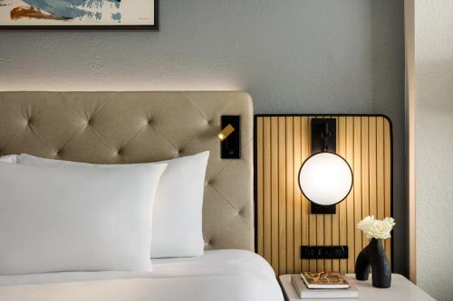 a bedroom with a bed with a white bedspread and a lamp at Crowne Plaza Virginia Beach Town Center by IHG in Virginia Beach