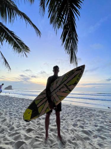 a man standing on the beach holding a surfboard at Tabularasa - T Palawan in San Vicente