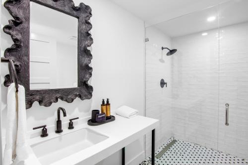 a white bathroom with a sink and a mirror at Captain’s Quarters at Anna Maria Island Inn in Bradenton Beach