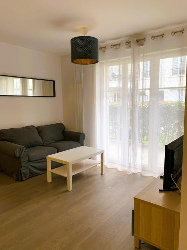 un salon avec un canapé et une table basse dans l'établissement Le Capitole, à Puteaux