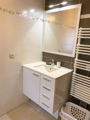 une salle de bain blanche avec un lavabo et un miroir dans l'établissement Le Capitole, à Puteaux