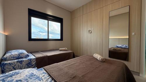 a bedroom with two beds and a window at IA02- 2 Quartos| Centro| Vista Mar| Churrasqueira in Itapoa