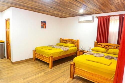 two beds in a room with yellow sheets at Corcovado & Drake Inn in Drake