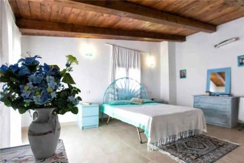 a bedroom with a bed and a vase with blue flowers at Holiday home in Sassari 53785 in Sassari