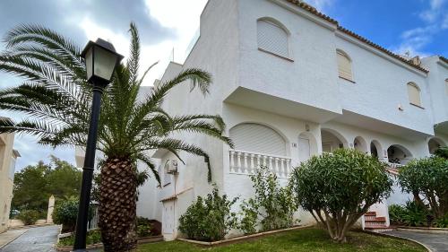 ein großes weißes Gebäude mit einer Palme davor in der Unterkunft Duplex en la playa in Puerto Marino