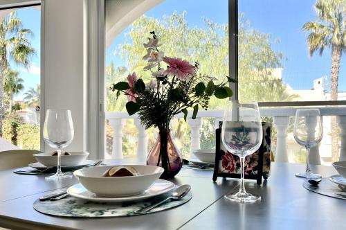 einen Tisch mit einer Vase aus Blumen und Gläsern darauf in der Unterkunft Duplex en la playa in Puerto Marino