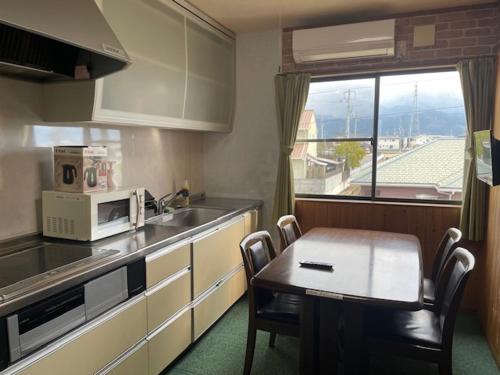 a small kitchen with a table and a microwave at 合同会社ゲストハウス縁 in Saijo