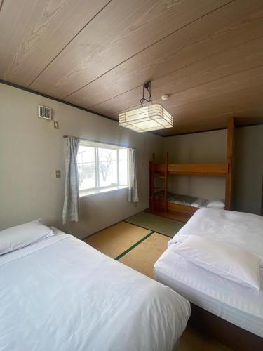 a bedroom with two twin beds and a window at Hakuba Cortina Backpackers in Otari