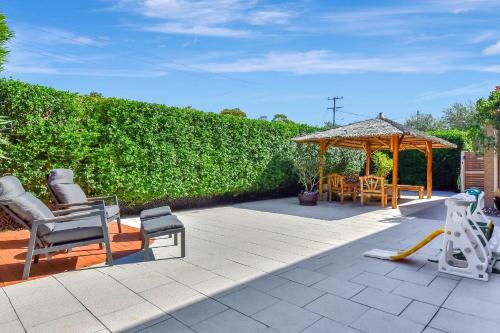 a patio with chairs and a wooden gazebo at Nelly's Nest in Nelson Bay