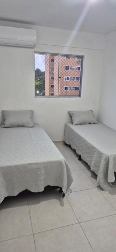 two beds in a white room with a window at Apartamento em Recife in Recife