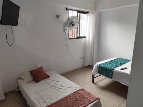 a room with a bed and a window with a fan at Wil Hostal Apt 203 in Cali