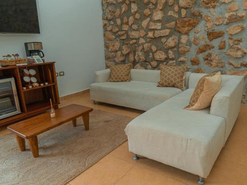a living room with two couches and a stone wall at Hotel Casa Puerta de Mar in Campeche