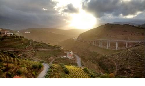 a view of a valley with the sun setting on a hill at Casa do Romezal in Peso da Régua