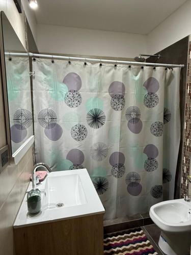 een badkamer met een wastafel en een douchegordijn met parasols bij Departamento Luz in Plottier