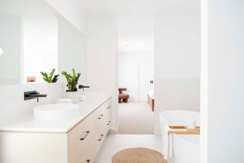 a white bathroom with two sinks and a mirror at Torquay Beach Getaway in Torquay