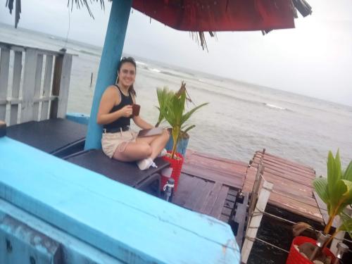 a woman sitting on the front of a house with the beach at Hotel Victoria s Beach House in Roatan