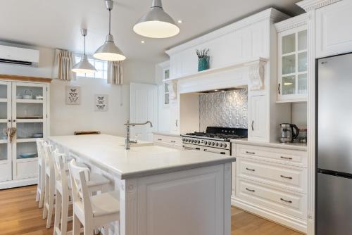 eine Küche mit weißen Schränken und einer Kücheninsel in der Unterkunft Bluestone Symmetrical Cottage with Outdoor Area in North Adelaide