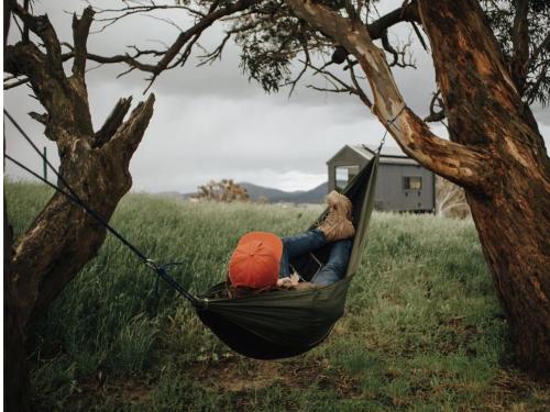 a person laying in a hammock under a tree at Remote Off-Grid Cabin Hidden in Nature - Hot Tub - Tibor in Oberon