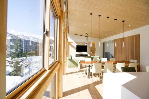 a dining room and living room with a large window at KYLA by Hakuba White Fox, Echoland Luxe w Mountain Views in Hakuba